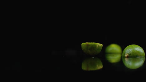 2-ripe-limes-fall-on-a-glass-with-splashes-of-water-in-slow-motion-on-a-dark-background